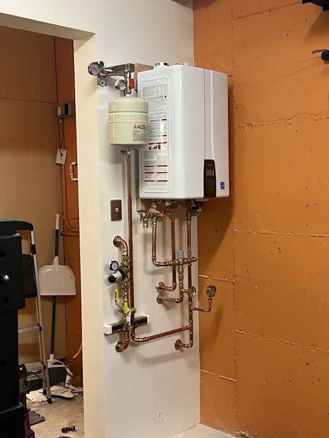 Plumbing technician inspecting water heater connections in Byron